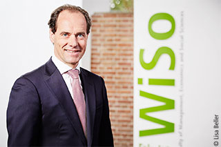 Prof. Werner Reinartz stehend vor dem WiSo Logo