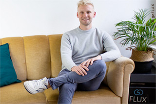 goFlux CEO Wolfram Uerlich in Jeans und Pullover auf einem gelben Sofa